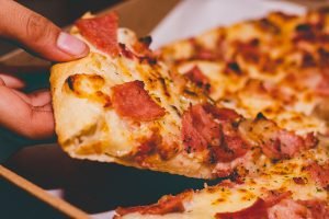 A person taking a slice of pizza