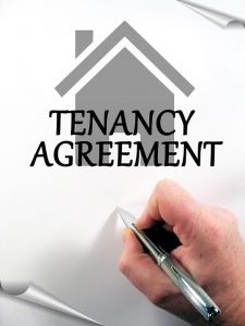 Tenancy agreement paper and a hand signing it. 