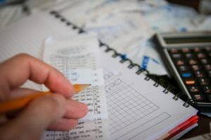 Bills, calculator and a hand with pen