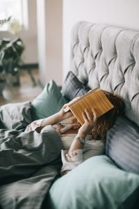 A woman laying in bed with a book on her face