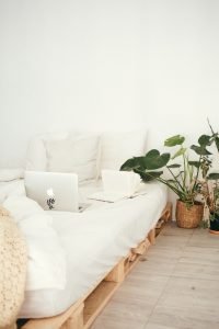 Packing a king-size bed with white sheets and a plant beside
