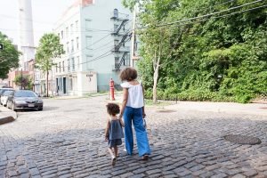 Mom and daughter walking away on cobble road